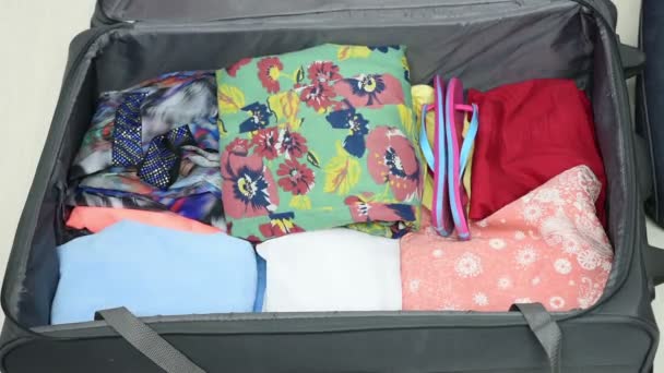 Κορίτσι συλλέγει ρούχα σε μια βαλίτσα. — Αρχείο Βίντεο