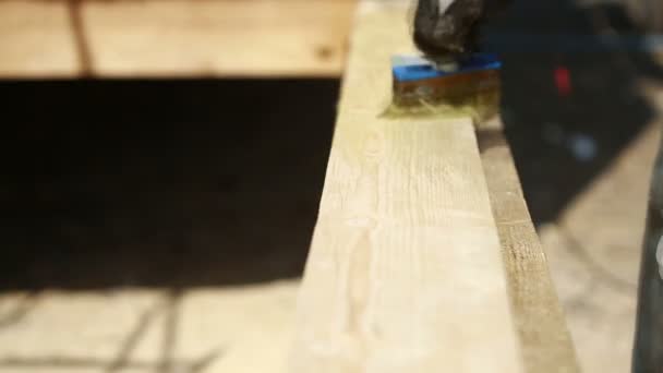 Een man schildert verf planken — Stockvideo