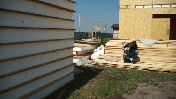 En man bygga ett hus. skumma polystyrenen. block av plywood och isolering. städning stuga. mätning tejp — Stockvideo