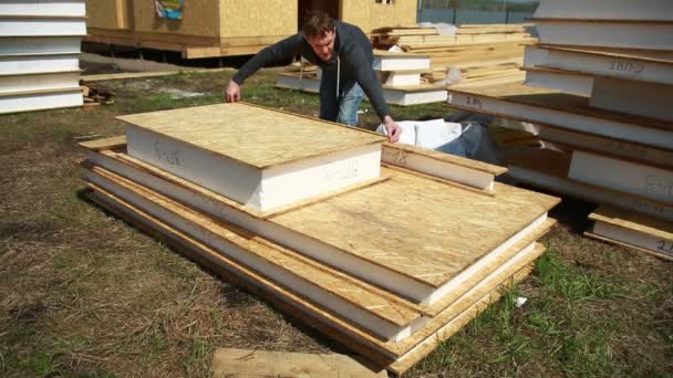 Un hombre construyendo una casa. espuma de poliestireno. bloques de madera contrachapada y aislamiento. casa de limpieza. cinta de medición — Vídeos de Stock