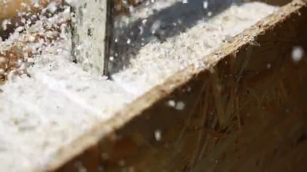 El serrín llena el aire cuando un carpintero usa una sierra circular eléctrica para cortar una hoja de madera contrachapada en un sitio de construcción. sierra de cadena — Vídeo de stock