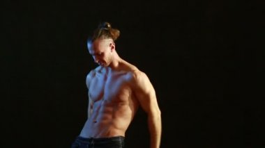 Kaslı adam vücut geliştiricisi. Adam siyah bir arka plan üzerinde poz kasları gösterir.