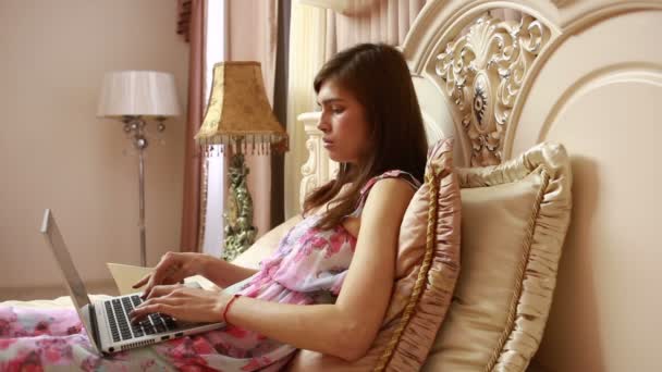 Mladé dívky pracuje na počítači v posteli. sociální sítě — Stock video