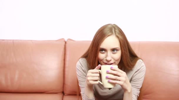 Portrait de jeune femme magnifique avec une tasse sur le canapé — Video