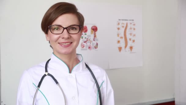 Porträt einer schönen, glücklichen Ärztin, die im Krankenhaus steht. Mädchen nimmt ihm die Brille vom Gesicht — Stockvideo