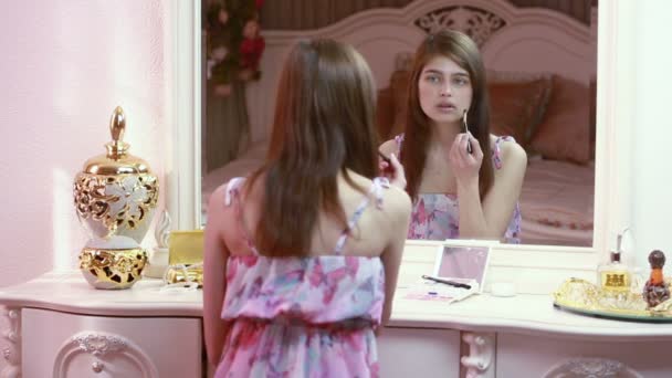 Beauty woman applying makeup. Beautiful girl looking in the mirror and applying cosmetic with a big brush. Girl gets blush on the cheekbones. — Stock Video