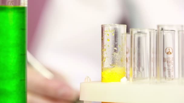 Mão enluvada segurando os tubos de ensaio no laboratório. É um processo químico — Vídeo de Stock