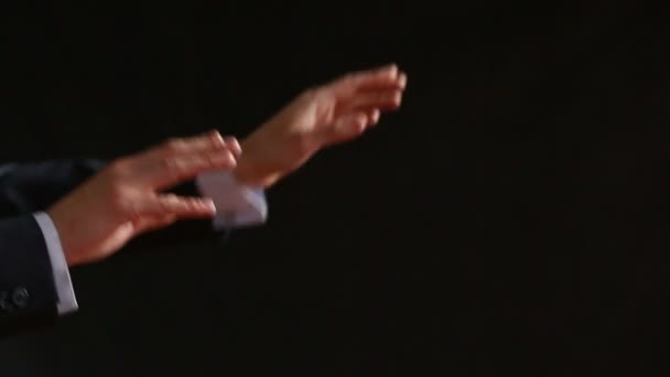 The moving hands of an orchestra conductor directing the musicians. Close-up shot. Black background — Stock Video