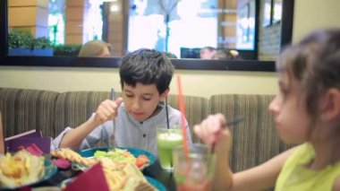 Çocuklar, kardeşim ve kız kardeşi kafede sandviç yeme. patates kızartması