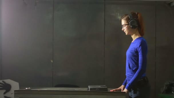 Mladá žena s pistolí na kryté střelnici. shromáždit zbraň — Stock video