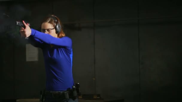 Bella giovane donna con la pistola su un poligono di tiro al coperto. spara una pistola — Video Stock