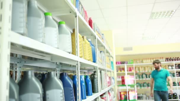 Hombre con bote de aceite de motor en tienda de automóviles — Vídeo de stock