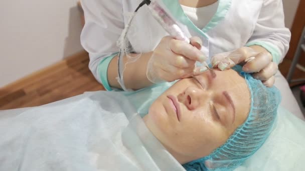 Cosmetoloog aanbrengen van permanente make-up op de wenkbrauw tatoeage — Stockvideo