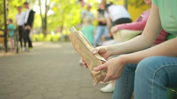 Meisje drinken uit een papieren zak in de straat. anti-sociaal gedrag — Stockvideo