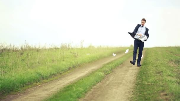 Geschäftsmann, der mit einem Stapel Papier im Wind steht. Dokumente werfen — Stockvideo