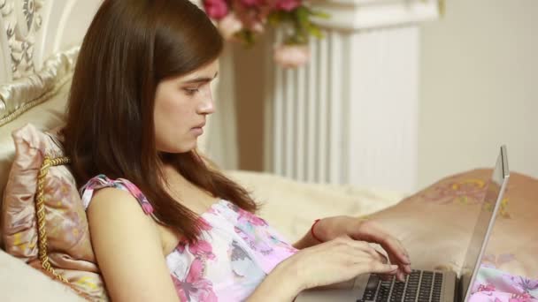 Une jeune fille qui travaille sur ordinateur au lit. réseaux sociaux — Video