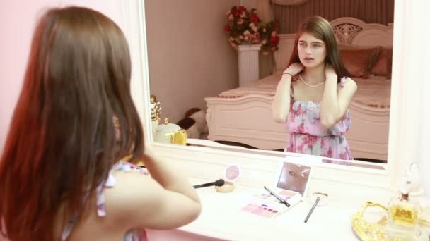 Девушка берет жемчужное ожерелье. Он сидит у зеркала. шикарный интерьер — стоковое видео