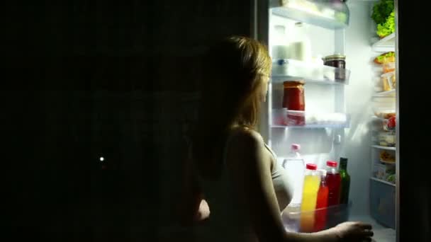 Femme ouvre le réfrigérateur la nuit. faim nocturne. régime alimentaire. gourmandise — Video