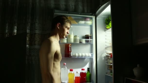 Homem comendo fora da geladeira à noite. comer maçã — Vídeo de Stock