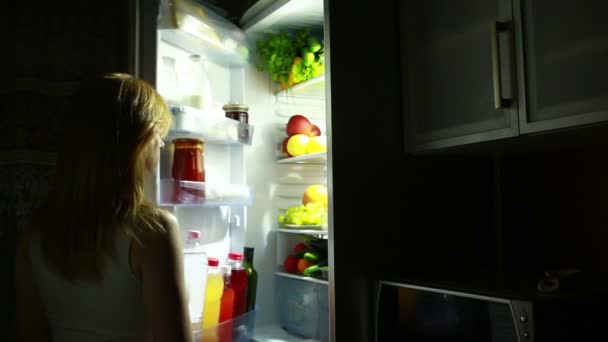 Жінка відкриває холодильник вночі. нічний голод. дієта. їдять виноград — стокове відео