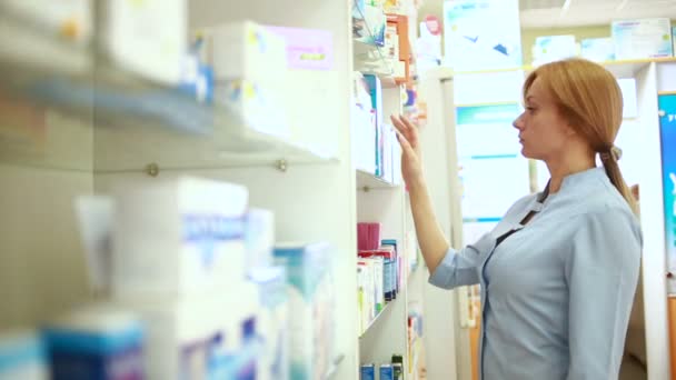 Женщина-фармацевт, стоящая за стойкой в аптеке — стоковое видео