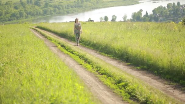 Dziewczyna idzie na wiejskiej drodze. — Wideo stockowe