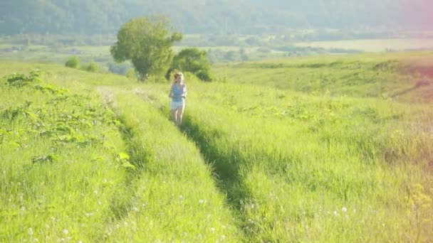 Kör kvinna. Flicka jogging på trail i bergen på fältet med gräs på sommaren. — Stockvideo