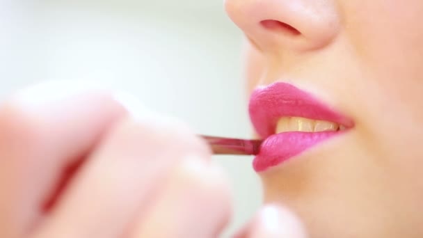 Närbild av ung kvinna läppar. make-up artist sätter läppstift borste — Stockvideo
