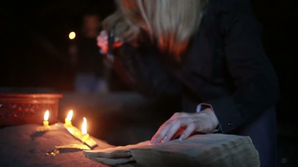 Відьма тримає магічний ритуал. стара книга та свічка. Хеллоуїн — стокове відео