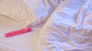 Young woman holding dildo on bed. sex toys