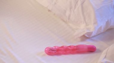 Young woman holding dildo on bed. sex toys