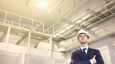 takım elbise ve kask adam. Bina olup olmadığını denetler. plana danışır