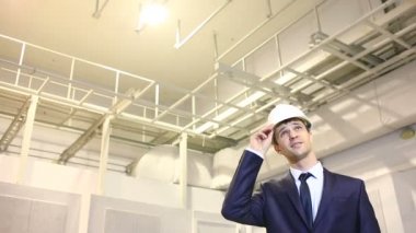 takım elbise ve kask adam. Bina olup olmadığını denetler. plana danışır