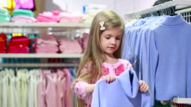 moda Dükkanı. küçük kız bir giyim mağazası. bir takım elbise seçer