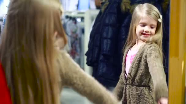 Fashionabla shop. liten flicka i en klädaffär. väljer en kostym — Stockvideo