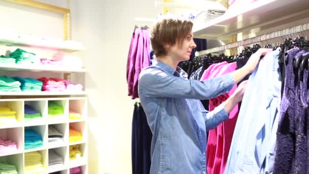 Довольно элегантная женщина делает покупки в магазине одежды — стоковое видео