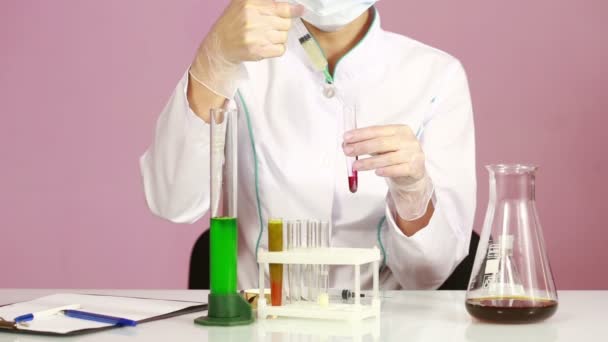 Female chemist comparing test tubes with chemicals. protective glasses — Stock Video