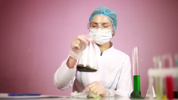 Female chemist comparing test tubes with chemicals. protective glasses — Stock Video