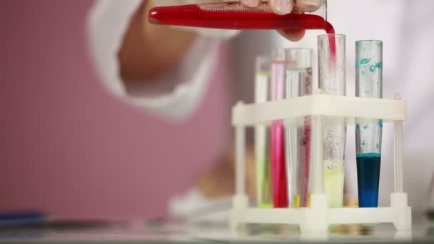 Química femenina comparando tubos de ensayo con productos químicos. gafas protectoras — Vídeo de stock