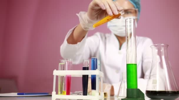 Female chemist comparing test tubes with chemicals. protective glasses — Stock Video