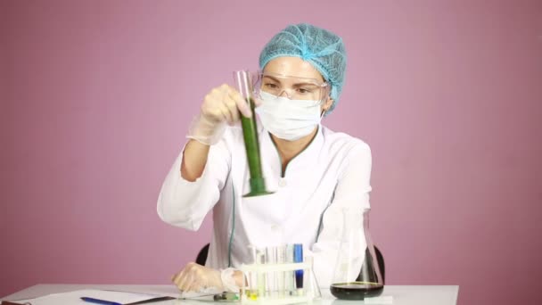 Жінка-хімік порівнює пробірки з хімікатами. захисні окуляри — стокове відео