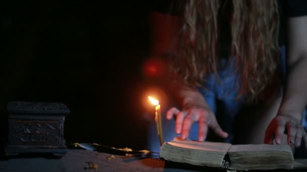 Bruja sosteniendo el ritual mágico. viejo libro y vela. Halloween. — Vídeos de Stock