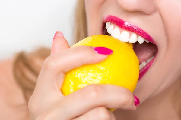 Girl biting a lemon Royalty Free Stock Images