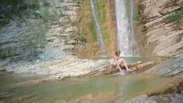 Сексуальна дівчина з бікіні приймає душ у водоспаді — стокове відео
