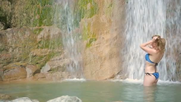 Сексуальная девушка в бикини принимает душ в водопаде — стоковое видео