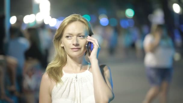Vacker kvinna med smartphone står i vattnet nattetid — Stockvideo