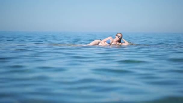 Menina sexy em biquíni azul se divertindo deitado na praia nas ondas — Vídeo de Stock