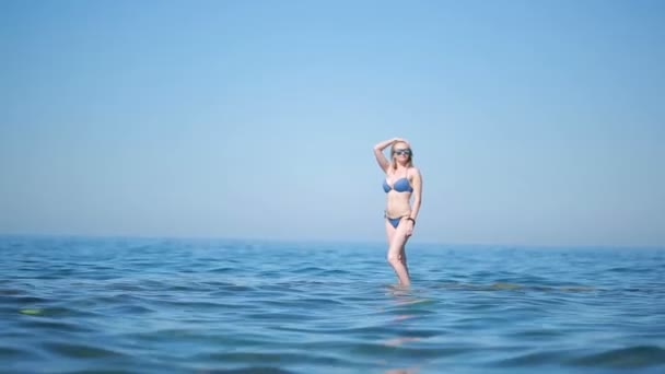 Sexy meisje in blauwe bikini plezier permanent in het water. op het strand in de golven — Stockvideo