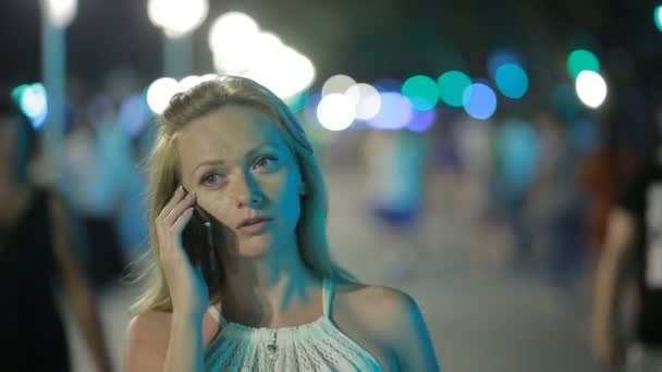 Красива жінка зі смартфоном, що стоїть на набережній вночі — стокове відео