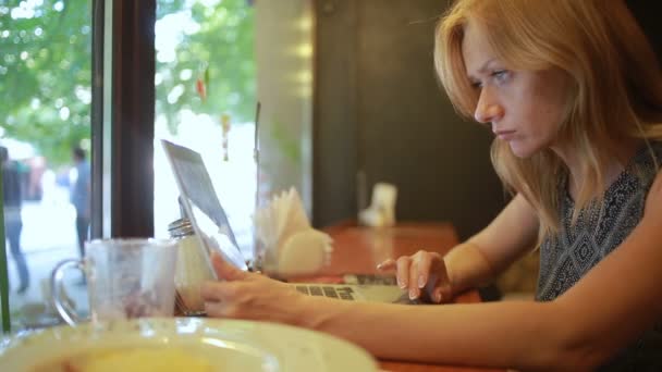 Mujer trabajando en la computadora portátil moderna en la cafetería — Vídeo de stock